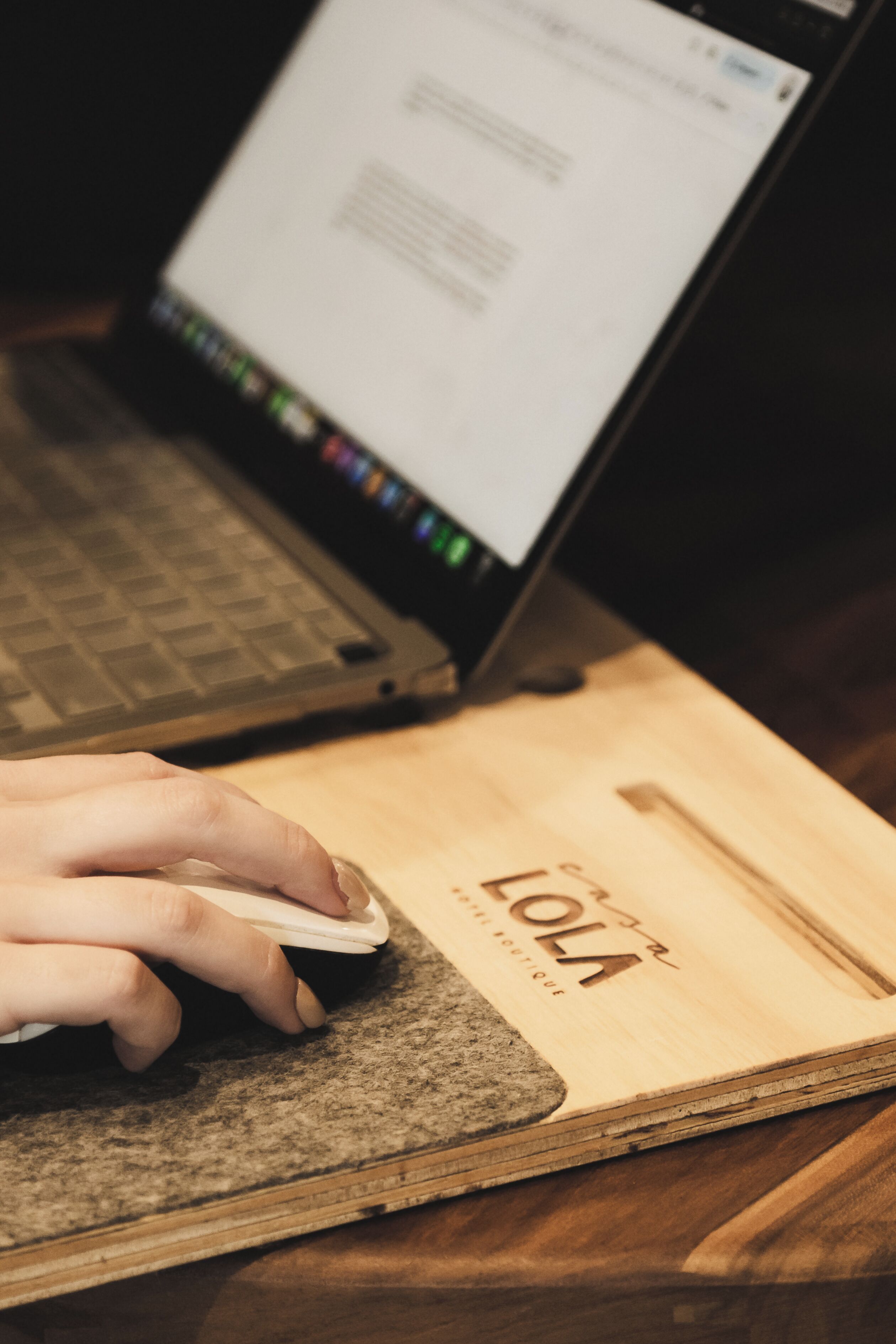 Una computadora portátil sobre una superficie de madera, con un teclado y una mano escribiendo.