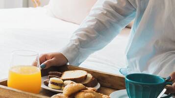 A breakfast tray with croissants, a glass of orange juice, and a blue mug on a wooden tray.