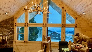 A log cabin interior with large windows, a chandelier, and wildlife taxidermy. - Imperial Elk Lodge-10 Miles to YNP+Sauna+Hot Tub+Wifi+AC (Island Park)
