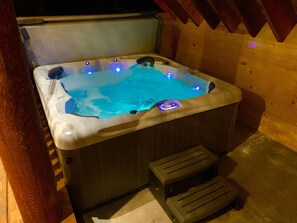 Un jacuzzi con revestimiento de madera y un escalón para entrar.