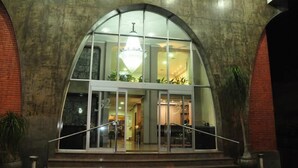 A building entrance with a glass facade, a chandelier, and a staircase leading up to the entrance. - Arua Hotel (Presidente Prudente)