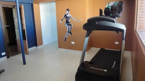 A gym with a treadmill, a mural of a person jumping, and a blue pillar. - Arua Hotel (Presidente Prudente)