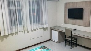 A small, clean room with a desk, chair, and a TV mounted on the wall. - Arua Hotel (Presidente Prudente)