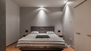 A modern bedroom with a large bed, nightstands, and a wardrobe.