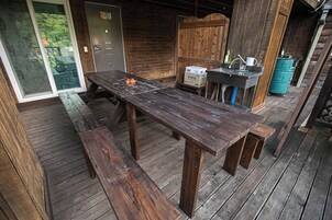 Una terraza de madera con una mesa de picnic, un lavamanos y un depósito de agua.