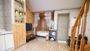 A room with a bed, a TV, a fan, a microwave, and a wooden cabinet. - Jirisan 1 Night 2 Days Pension (Gurye)