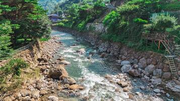 Un río serpentea por un paisaje rocoso con un muro de piedra y un puente de madera.