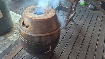 A large, rusted metal container with a small opening emitting steam, placed on a wooden deck.
