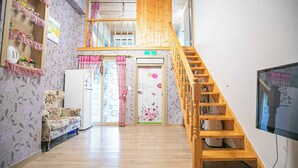 A multi-level interior with a wooden staircase, a sofa, a refrigerator, and a television. - Jirisan 1 Night 2 Days Pension (Gurye)