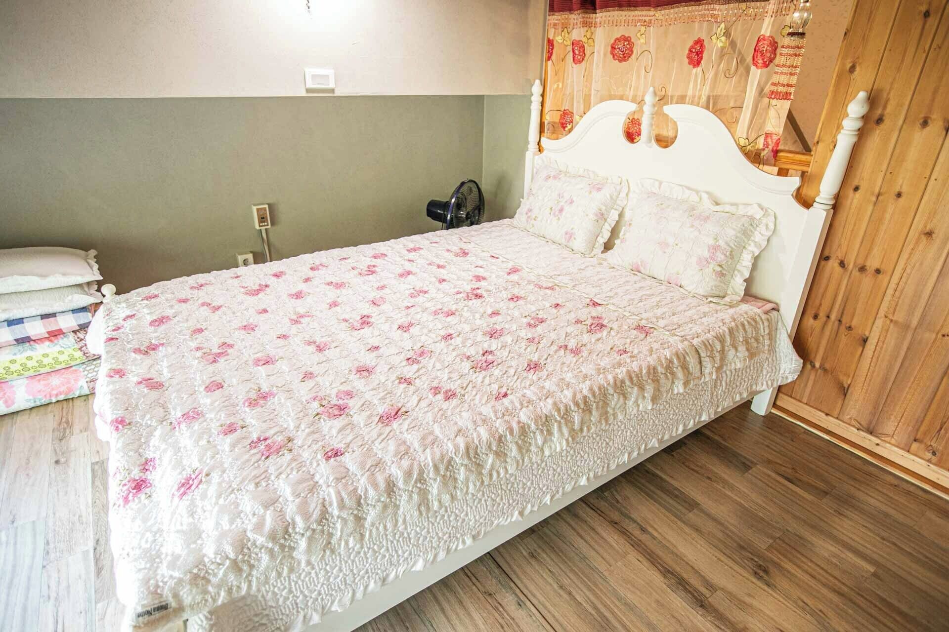 Una cama individual con colcha estampada, una mesita de noche con lámpara y un cabecero de madera.
