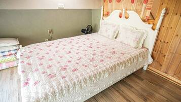 Una cama individual con colcha estampada, una mesita de noche con lámpara y un cabecero de madera.