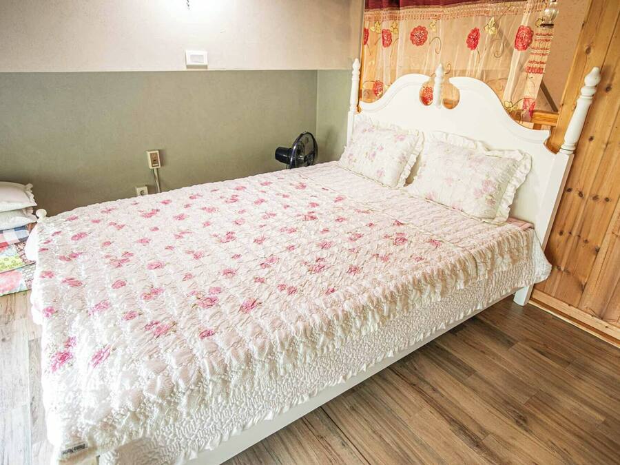 Una cama individual con colcha estampada, una mesita de noche con lámpara y un cabecero de madera.