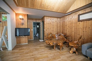 Una habitación con paneles de madera, un televisor, una mesa de comedor con sillas y un sofá.