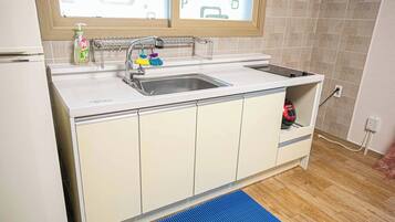 A kitchen with a sink, a window above it, and a blue mat on the floor.