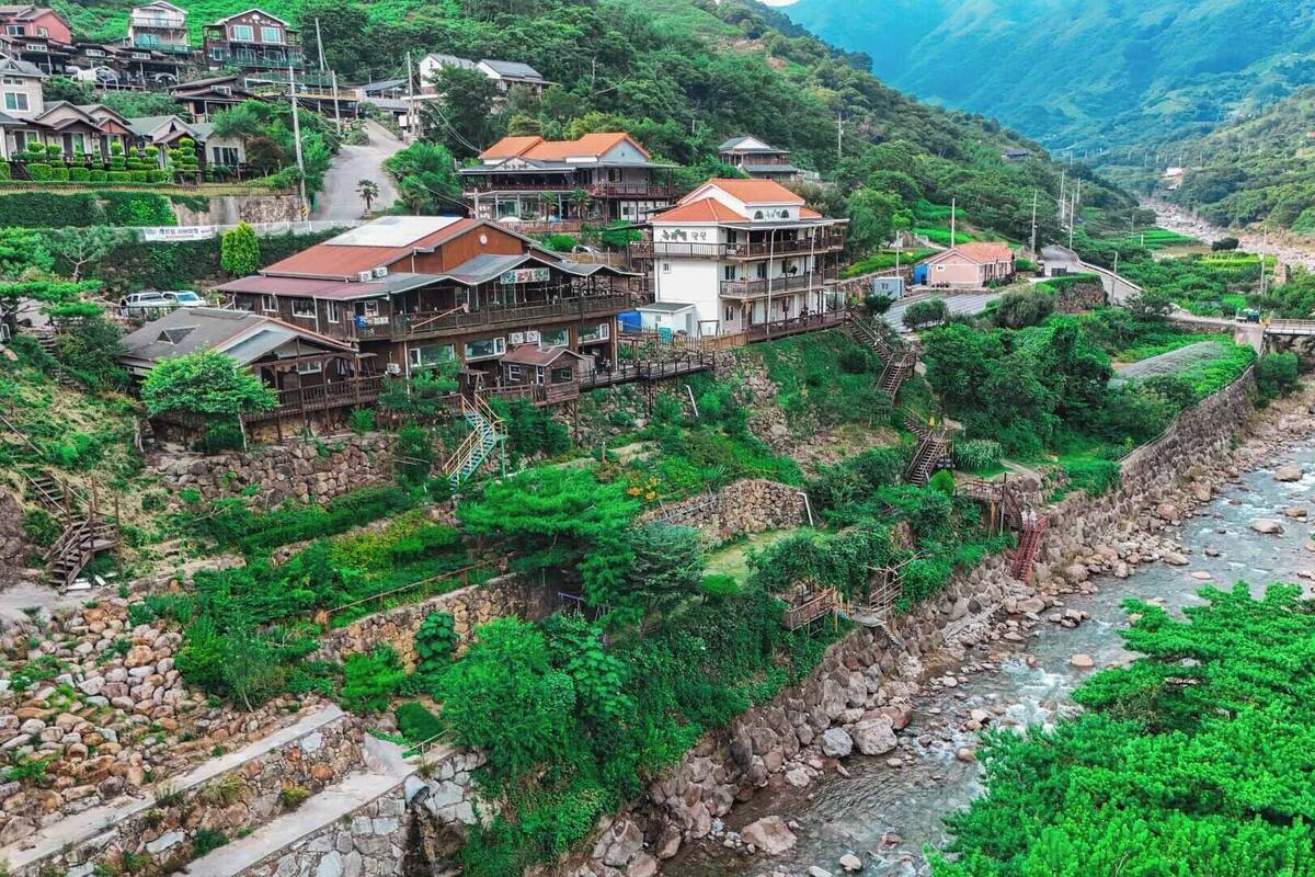 Un pueblo en una ladera con casas tradicionales, un río y un puente.