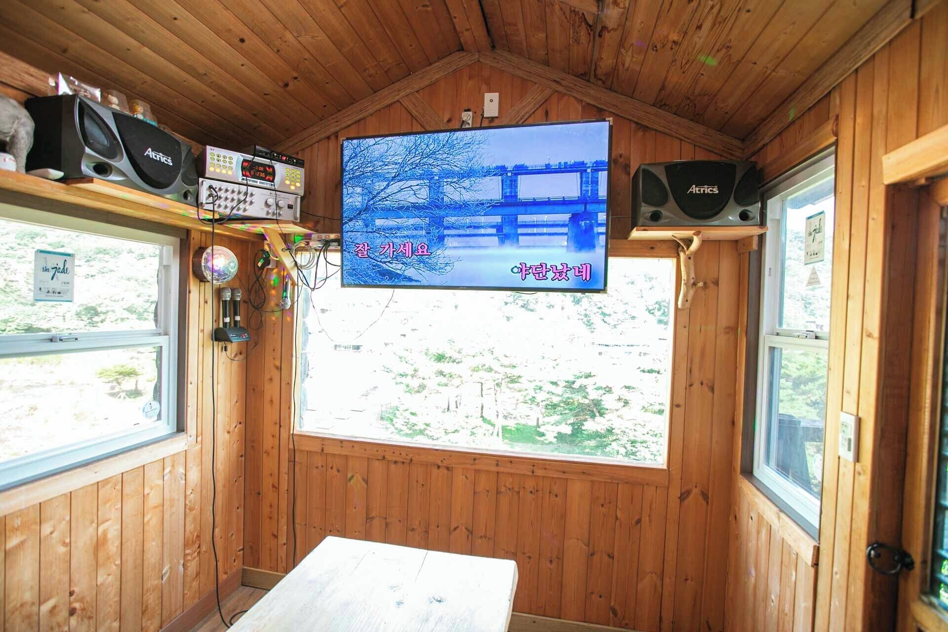 Una cabaña de madera con un televisor que muestra un puente, altavoces y una mesa.