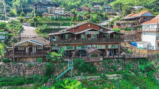 A multi-story house with a balcony, a stone wall, and a staircase leading to the entrance. - Jirisan 1 Night 2 Days Pension (Gurye)