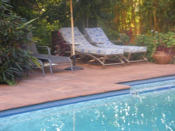 Relax by the serene pool surrounded by lush greenery and comfortable lounge chairs.