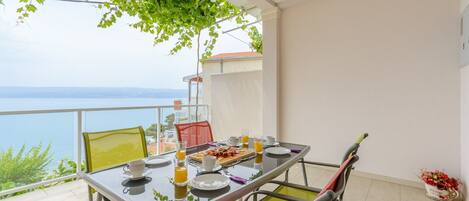 Ein Balkon mit gedecktem Tisch für ein Frühstück, mit Blick auf ein Gewässer.