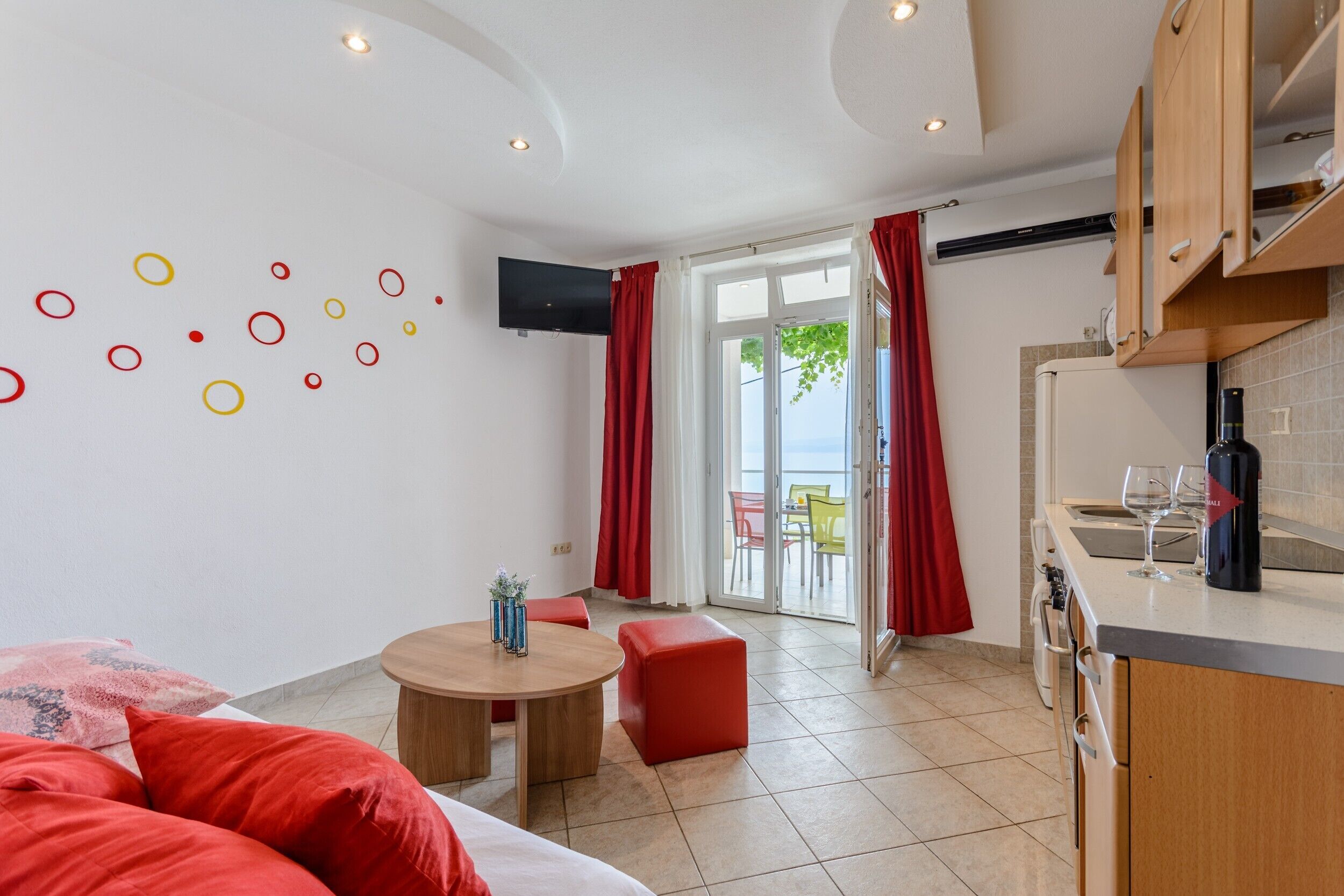 A modern room with a bed, a round table, and a kitchen area.