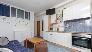 A compact kitchen with white cabinets, a microwave, a coffee maker, and a built-in oven. There is a wooden table and a bench in the living area. - Apartments Hope (Dugi Rat) - One-Bedroom Apartment with Terrace and Sea View (A2) (Dugi Rat)