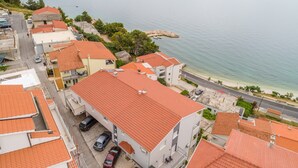 A coastal residential area with red-tiled roofs, a beach, and a marina. - Apartments Hope (Dugi Rat) - One-Bedroom Apartment with Terrace and Sea View (A2) (Dugi Rat)