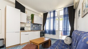 A compact living space with a kitchenette, a sofa with patterned upholstery, and a wooden table. - Apartments Hope (Dugi Rat) - One-Bedroom Apartment with Terrace and Sea View (A2) (Dugi Rat)