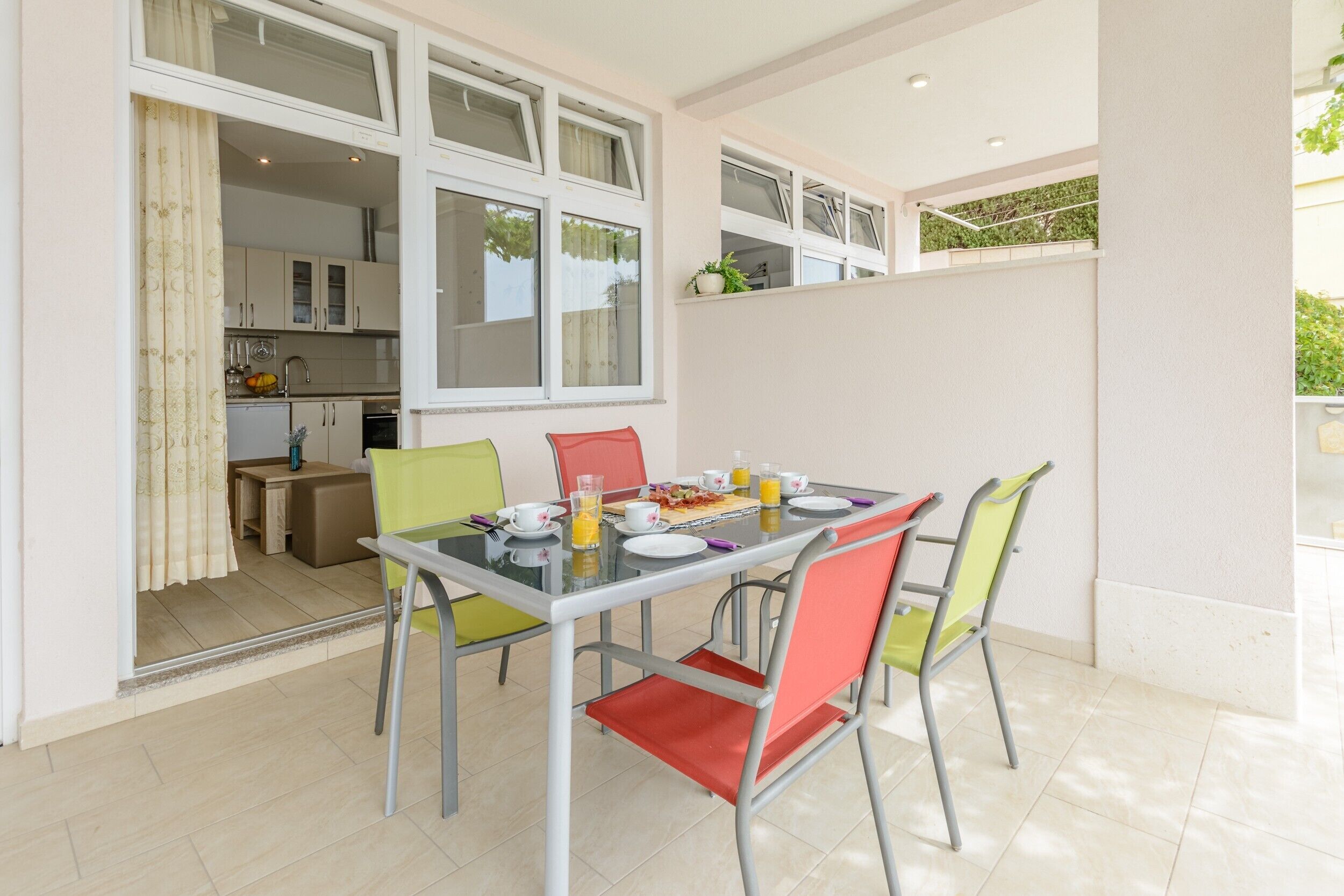 A dining area with a table set for two, chairs, and a breakfast spread including toast, eggs, and juice.