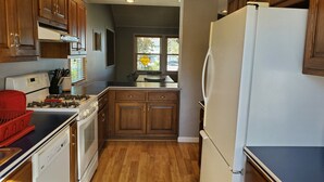 A kitchen with wooden cabinets, a white refrigerator, and a stove. - Rye Beach Lake Front Home near Cedar Point (Huron)