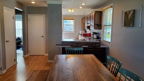 A kitchen with a dining table and chairs, a window with blinds, and a door leading to another room. - Rye Beach Lake Front Home near Cedar Point (Huron)