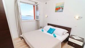 A neatly made bed with a white and blue pillow, a wooden floor, a nightstand with a lamp, and a painting on the wall. - Holiday Home Adriatic View-Five Bedroom Holiday Home with Pool and Sea View (Blato)