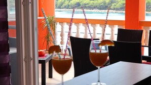 A table with two drinks and a plant on a balcony overlooking a beach. - Holiday Home Adriatic View-Five Bedroom Holiday Home with Pool and Sea View (Blato)