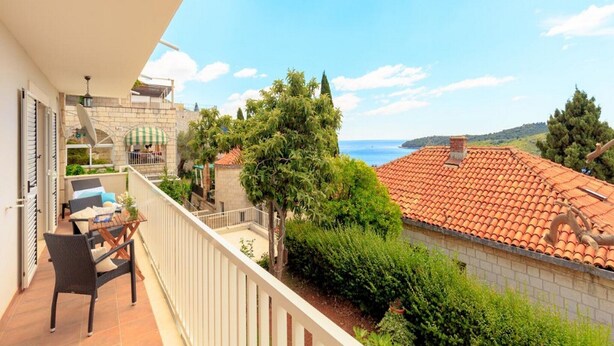 Un balcon avec vue sur la mer, un coin repas avec des chaises et une table, et une antenne parabolique.
