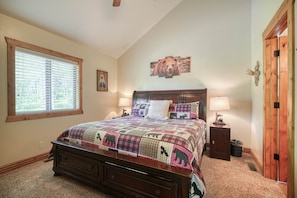 A bedroom with a large bed, a window, a wooden door, and a wall-mounted artwork. - Nestled in the mountains, 20 min ➡️ Yellowstone,  AC, WI-FI, Large Porch 🏕️ (Island Park)