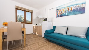 A modern living room with a teal sofa and a dining area with a wooden table and chairs. - Villa LA-Comfort One Bedroom Apartment with Sea View Terrace 1 (Drvenik Veliki)