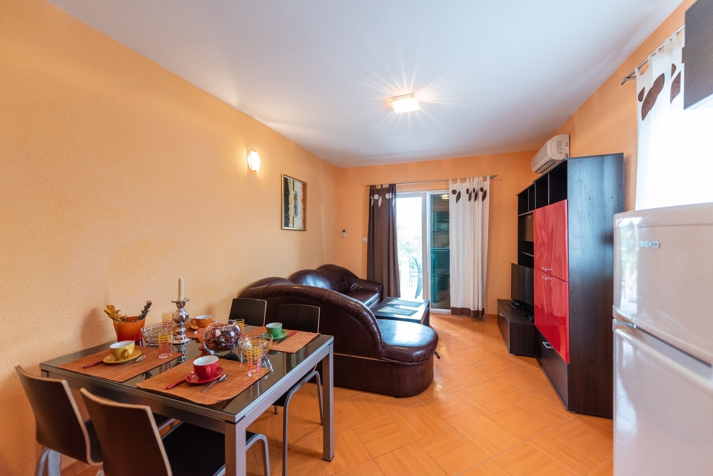 Un espace de vie compact comprenant un coin repas, un canapé, une kitchenette et un réfrigérateur.