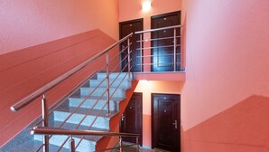 Uma escadaria com grades de metal que leva a um patamar com duas portas.