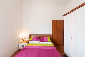 A bedroom with a bed, nightstand, and wooden wardrobe. - Apartments Karen - Comfort Two Bedroom Apartment with Balcony (A4) (Vinisce)