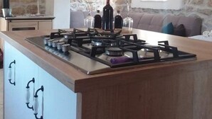 Een keuken met een centraal eiland, stenen muren en een zithoek met een bank.