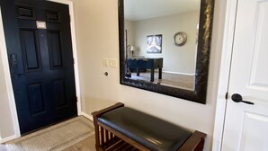 A hallway with a wooden bench, a large mirror, and a black door. - Your perfect AZ getaway with putting green and optional HEATED private pool! (Chandler)