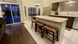 A kitchen with a bar area, a dining area, and a sliding glass door leading to a patio. - Your perfect AZ getaway with putting green and optional HEATED private pool! (Chandler)