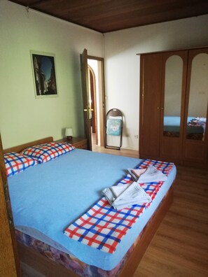 Una habitación con cama, armario, espejo y puerta.