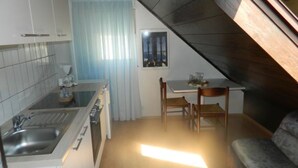 Una cocina compacta con comedor, una ventana con cortinas y techo de madera.