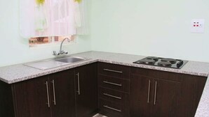 Una cocina con armarios de madera oscura, encimera de granito, pileta de acero inoxidable y cocina a gas.