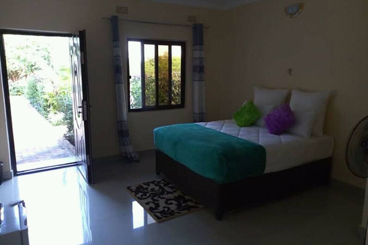 A bedroom with a bed, a window, and a door leading outside.