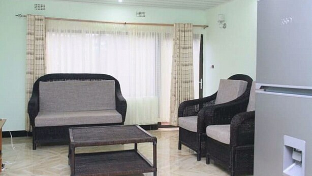 Una sala de estar con un sofá, dos sillones, una mesa de centro y un refrigerador.