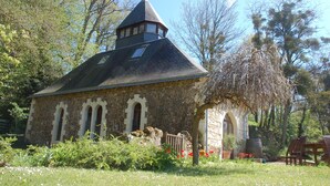 Une église en pierre, dotée d’un toit conique et de fenêtres en arc de cercle.
