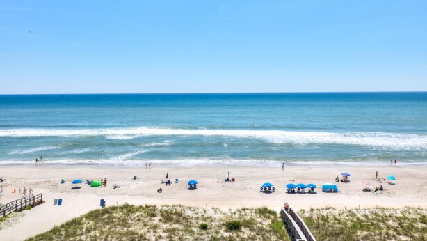 A beach with umbrellas, sun loungers, and a boardwalk. - 🏖️Pelican Watch 302: Oceanfront | Indoor + Outdoor Pool | Hot Tub🏖️ (Carolina Beach)
