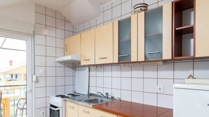 Una cocina compacta con estufa, lavamanos y armarios.