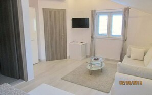 Relax in this stylish living room with a flat-screen TV, glass coffee table, and comfortable sofa.